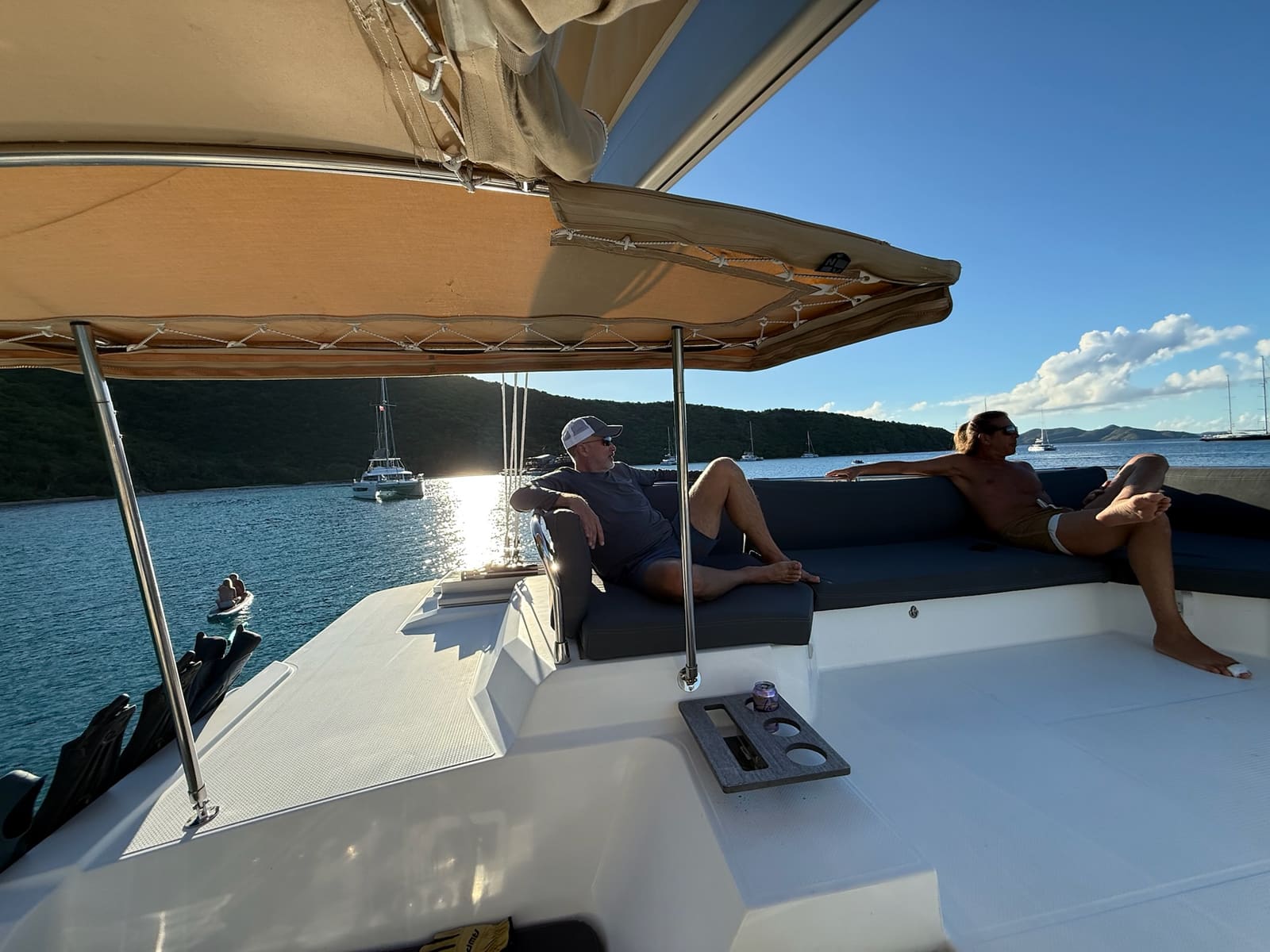 Guests lounging on the shaded foredeck seating at anchor