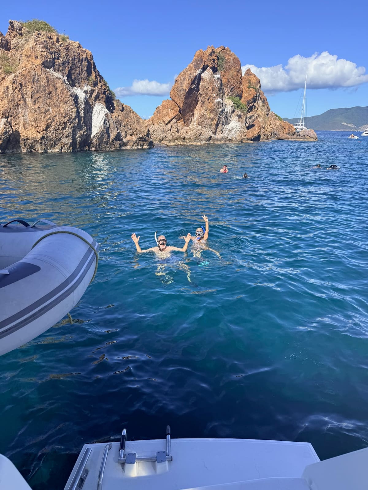 Two guests snorkeling off the stern near rock formations