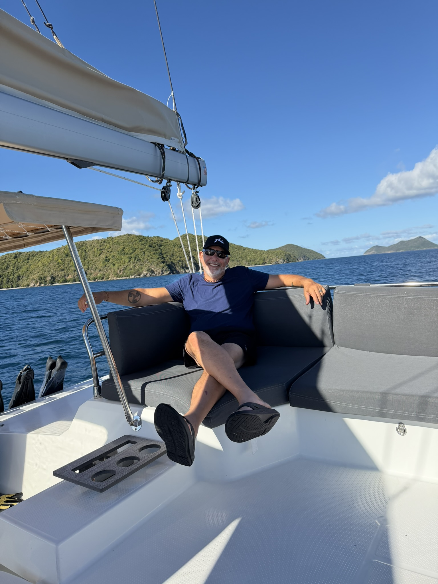 Clint Kendall relaxing in the cockpit of the catamaran, a British Virgin Islands headland behind him