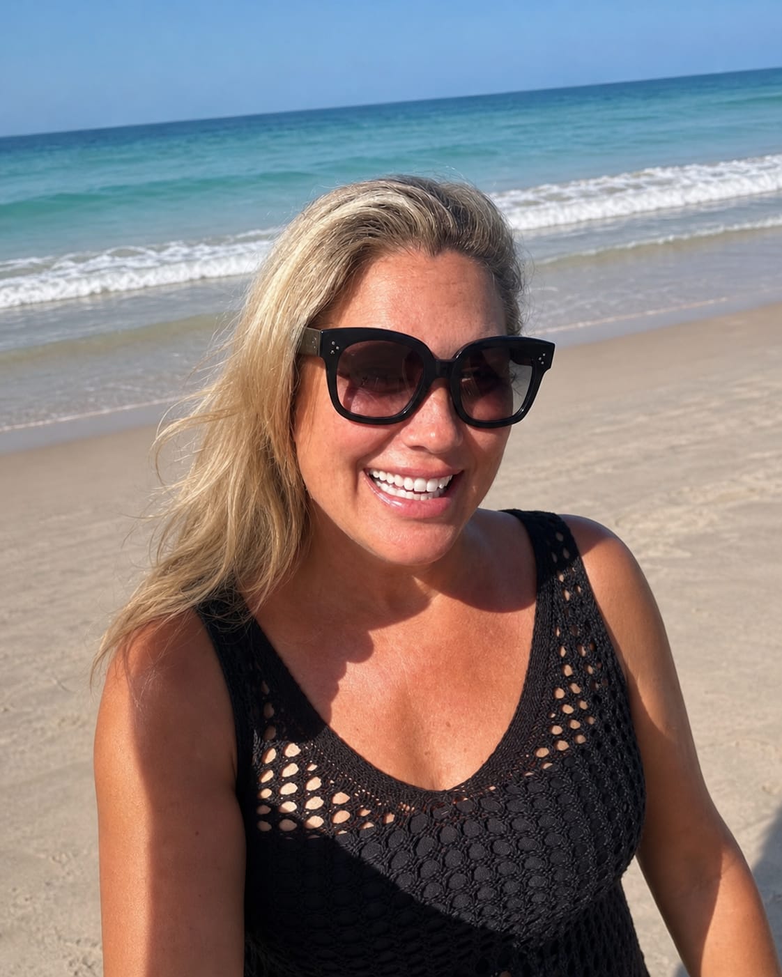 Dodie Kendall smiling on the beach, the Caribbean surf behind her